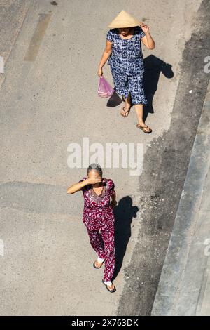 SAIGON, VIETNAM, 17. Dezember 2017, Frauen gehen die Straße hinunter und verstecken ihre Gesichter vor der Sonne Stockfoto