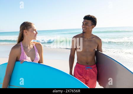 Am Strand, verschiedene Paare halten Surfbretter und lachen zusammen Stockfoto