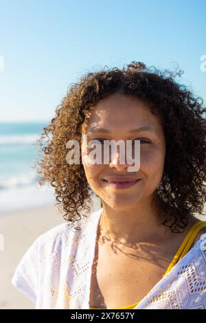 Am Strand, eine Frau mit weißem Oberteil, die in die Kamera lächelt Stockfoto