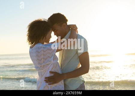Am Strand, verschiedene Paare umarmen, Sonnenuntergang beleuchtet den Himmel Stockfoto