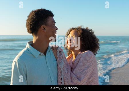 Am Strand stehen verschiedene Paare, die zusammen lachen Stockfoto