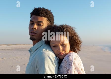 Am Strand, ein birassisches Paar, das sich umsorgt und nachdenklich aussieht Stockfoto