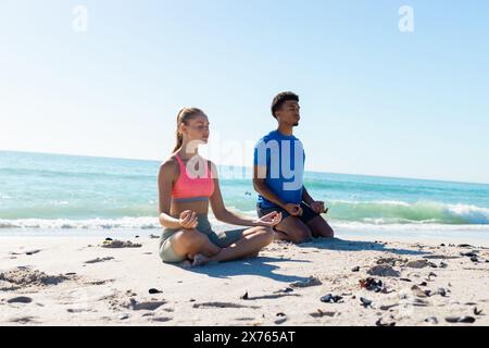 Am Strand praktizieren verschiedene Paare gemeinsam Yoga Stockfoto