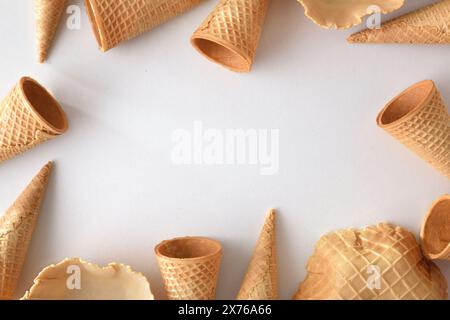 Rahmen mit kegelförmigen und schalenförmigen Waffeln für Eis auf weißem Tisch. Draufsicht. Stockfoto