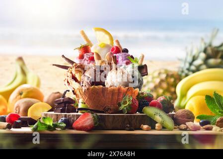 Verschiedene Obsteis auf Holztisch mit Kugeln, die mit Zutaten am Strand dekoriert sind. Vorderansicht. Stockfoto
