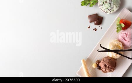 Hintergrund von Eiskugeln verschiedener Geschmacksrichtungen in Behältern und Zutaten isoliert auf weißem Tisch Stockfoto