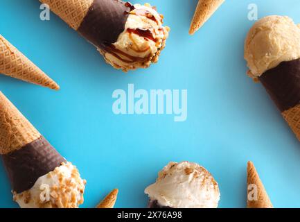 Rahmen mit Eiskegeln verschiedener Geschmacksrichtungen mit Schokoladentegel auf blauem Hintergrund Stockfoto