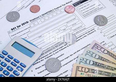 Ein Taschenrechner und einige US-Dollar-Münzen und -Banknoten oben auf dem Formular „Quarterly Federal Tax return“ (vierteljährliche Steuererklärung des Arbeitgebers). Stockfoto