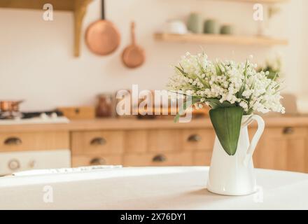 Blumenstrauß von Frühlingsblüten von Lilien des Tales in einer Vase auf dem Küchentisch. Leichter skandinavischer Stil. Muttertag. März, Internatio Stockfoto