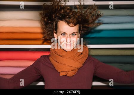 Fröhliche junge Frau mit lockigem Haar in einem Stoffgeschäft Stockfoto