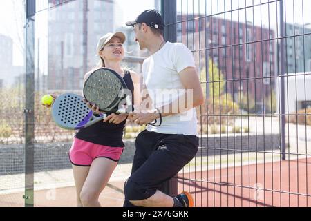 Porträt von zwei lächelnden Sportlern, die auf dem Padel-Platz im Freien mit Schlägern posieren - Padel-Spieler Stockfoto