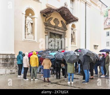 Gruppe von Touristen mit Sonnenschirmen vor der Kathedrale St. Nikolaus, Ljubljana, Slowenien, an einem nassen Tag. Stockfoto