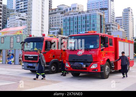 Das tägliche Leben in Nha Trang, Vietnam, Asien. Die Mitarbeiter der Feuerwehr bereiten sich auf eine Sicherheitsvorstellung am Meer vor, an der zwei Feuerwehrfahrzeuge geparkt sind Stockfoto