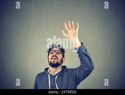 Junger Mann mit erhobener Hand, der versucht, etwas oben zu fangen Stockfoto