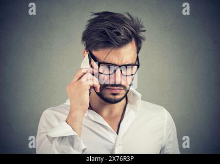 Nahaufnahme Porträt eines traurigen unglücklichen jungen Mannes, der auf einem Handy spricht Stockfoto