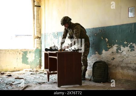 Militärische Mission. Soldat in Uniform mit Laptop am Tisch im verlassenen Gebäude Stockfoto