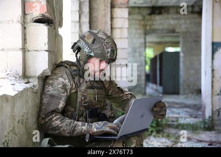 Militärische Mission. Soldat in Uniform mit Laptop im verlassenen Gebäude Stockfoto