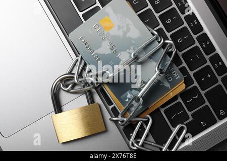 Cybersicherheit. Metallschloss mit Kette und Kreditkarten am Laptop, Draufsicht Stockfoto