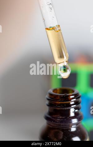 Nahaufnahme Des Tropfens Mit Flüssigkeit Über Brauner Flasche. Ein Nahbild, das einen Tropfer zeigt, der einen Tropfen Flüssigkeit in eine braune Glasflasche abgibt. Stockfoto