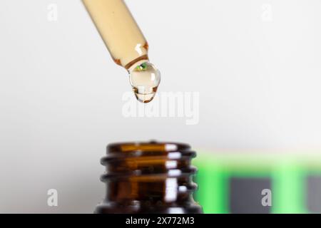 Nahaufnahme Des Tropfens Mit Flüssigkeit Über Brauner Flasche. Ein Nahbild, das einen Tropfer zeigt, der einen Tropfen Flüssigkeit in eine braune Glasflasche abgibt. Stockfoto
