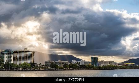 Die Sonne fließt durch eine Lücke in den Wolken auf die Esplanade und Hotels mit Blick auf den Hafen von Cairns in North Queensland, Australien Stockfoto