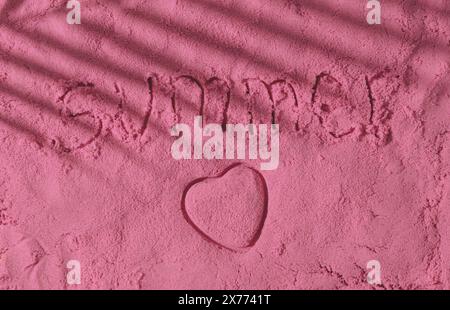 Das Wort Sommer handgeschrieben und Herzform auf rosa Sandoberfläche mit tropischem Palmenblattschatten. Minimales Konzeptfoto von Sommerferien. Stockfoto