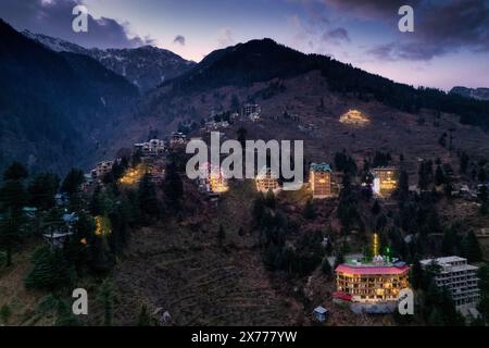 Drohnenlandung aus der Luft mit beleuchteten mehrstöckigen Gebäuden am Abend auf der Seite des Hügels, wobei die Einkaufsviertel der Hotels in manali, shimla, gezeigt werden Stockfoto