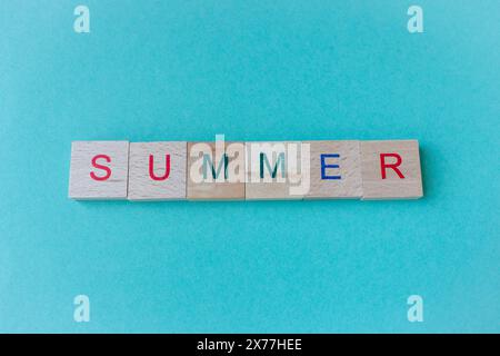 Wortsommer aus Holzstücken auf azul Hintergrund. Sommerferienkonzept. Sommer-Lifestyle. Text auf blauem Hintergrund mit Kopierraum. Stockfoto