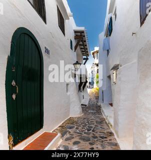 Binibeca Vell, Spanien - 24. Januar 2024: Enge Gasse führt durch ein Labyrinth von weiß getünchten Gebäuden im Dorfzentrum von Binibeca Vell Stockfoto