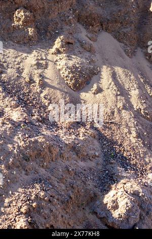 Eine Mischung aus Boden, braunem Grundgestein und kleinen Felsen, die einer Mini-Landschaft ähneln. Das Gesteinsmuster schafft einen interessanten Kontrast im grasbewachsenen Bereich Stockfoto