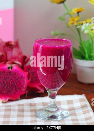Ein Glas Saft und Stücke roter Drachenfrucht auf einem Tisch, der mit Tuch dekoriert ist Stockfoto