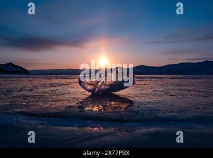 Eiskristall auf der gefrorenen Oberfläche des Baikalsees am frühen Morgen. Himmel- und Sonnenstrahlen auf der Eisoberfläche. Herrliche Winterlandschaft. Winter Stockfoto