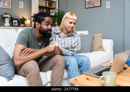 Junger Mann und Frau, glückliches Paar, das mit einem freundlichen Psychologen spricht, während er von zu Hause aus einen Videoanruf in die Klinik macht. Beziehungsschwierigkeiten, mit Witz zu lösen Stockfoto