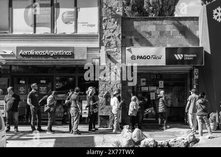 Personen, die sich vor Einem Büro von Pago Facil/Western Union in El Calafate, Patagonien, Argentinien, in Warteschlangen befinden. Stockfoto