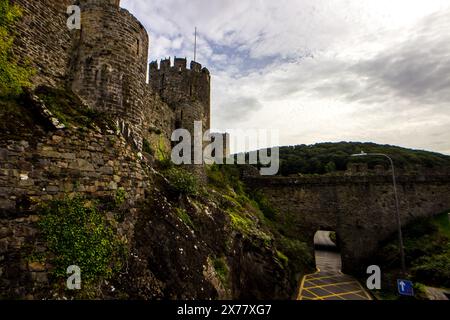 Die mittelalterlichen Mauern von Conwy ragen über die Straße, die zum mittelalterlichen Stadtzentrum führt Stockfoto