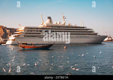 Eine Superyacht des Sultans von Oman legte im Sultan Qaboos Port in Maskat, Oman an. Eine hölzerne Dau ist davor verankert Stockfoto