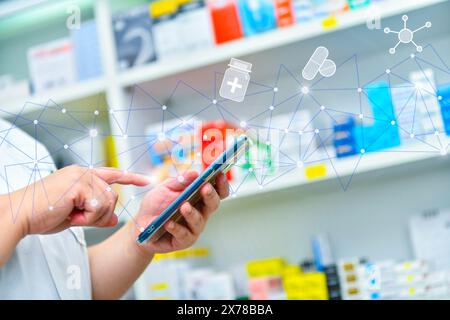 Ein Apotheker hält ein Mobiltelefon, um ein ärztliches Rezept zu erhalten, Medikamente zuzubereiten und Medikamente in einer Apotheke zu überprüfen. Stockfoto