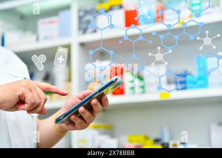 Ein Apotheker hält ein Mobiltelefon, um ein ärztliches Rezept zu erhalten, Medikamente zuzubereiten und Medikamente in einer Apotheke zu überprüfen. Stockfoto