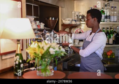 Der konzentrierte Barista bereitet den Kaffee sorgfältig an einer Espressomaschine in einem komfortablen, warm beleuchteten Café-Ambiente zu Stockfoto