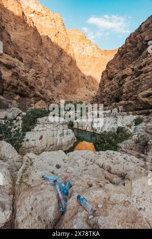 Plastikflaschen schmücken die felsige Landschaft von Wadi Shab, Oman und zeigen die touristische Verschmutzung in einer empfindlichen Wüstenschlucht und natürlichen Wasserstraße Stockfoto