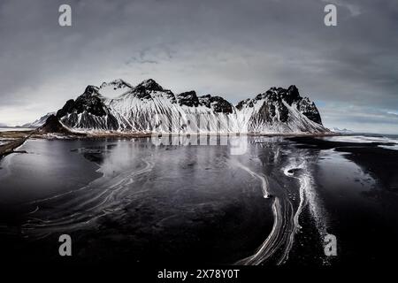 Schneebedeckte Vestrahorn-Berge spiegeln sich im eisigen Wasser am Stokksnes Beach im Südosten Islands. Stockfoto