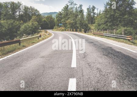 Leere Asphaltstraße in den Bergen durch den Kiefernwald in Rumänien. Stockfoto