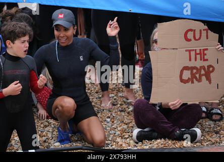 Brighton, England, Großbritannien. Mai 2024. DAME KELLY HOLMES schließt sich den Demonstranten am Strand an, eine hält ein Schild mit der Aufschrift "˜du bist der Mist" während der Proteste in der Nähe des West Pier. Surfers Against Sewage (SAS) und ihre Unterstützer gingen ins Meer, um die Menge an Abwasser hervorzuheben, die in Sussex's Wasserstraßen gepumpt wurde. Viele von denen, die in schicken Kleidern zum Thema Abwasser aufs Meer gingen, sagten, sie seien beim Schwimmen bereits krank geworden. SAS ist eine Wohltätigkeitsorganisation für Meeresschutz, die mit Gemeinden zum Schutz der Ozeane, Strände und Meereslebewesen zusammenarbeitet. (Kreditbild: © Martin Pope/ZUMA Press Wire) REDAKTIONELLE VERWENDUNG Stockfoto