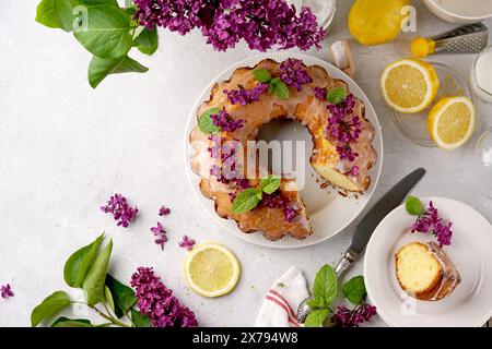 Stillleben von Zitronenkuchen mit Scheibe und Flieder auf weißem Hintergrund. Draufsicht, Kopierraum Stockfoto