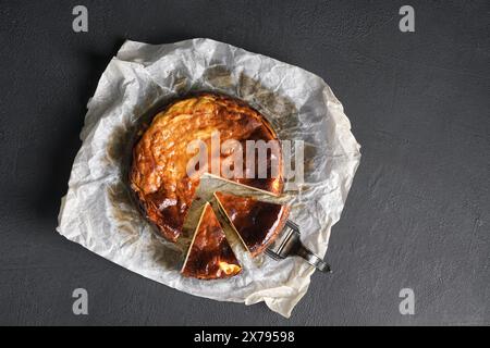 Blick von oben auf den baskischen, verbrannten Käsekuchen auf einem schwarzen Tisch. Kopierbereich Stockfoto