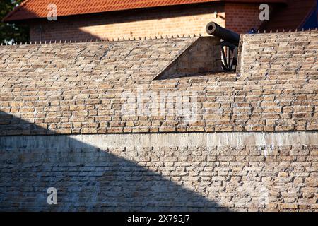 Eine alte Ziegelmauer der Festung. Eine große Stahlkanone oben auf der Wand. Hintergrund. Textur. Horizontal. Stockfoto