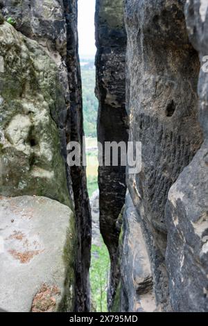 Eine Felswand mit einer kleinen Öffnung darin. Die Öffnung ist dunkel und schmal. Die Felsmauer besteht aus schwarzem Stein Stockfoto