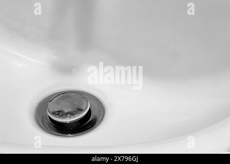 Detail eines weißen Keramikwaschbeckens in einem modernen Badezimmer mit verchromtem Abfluss. Horizontal. Für Text. Stockfoto
