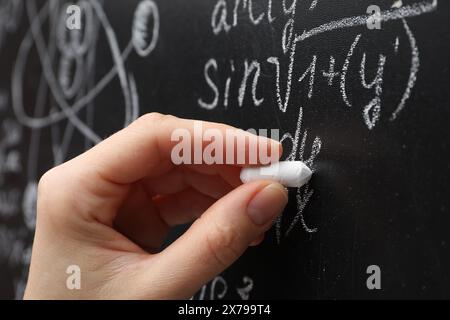 Der Lehrer schreibt mathematische Formeln mit Kreide auf der Tafel, Nahaufnahme Stockfoto