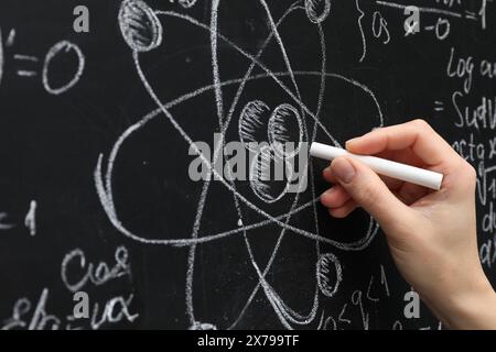 Lehrer schreibt physikalische Formeln mit Kreide auf schwarzer Tafel, Nahaufnahme Stockfoto